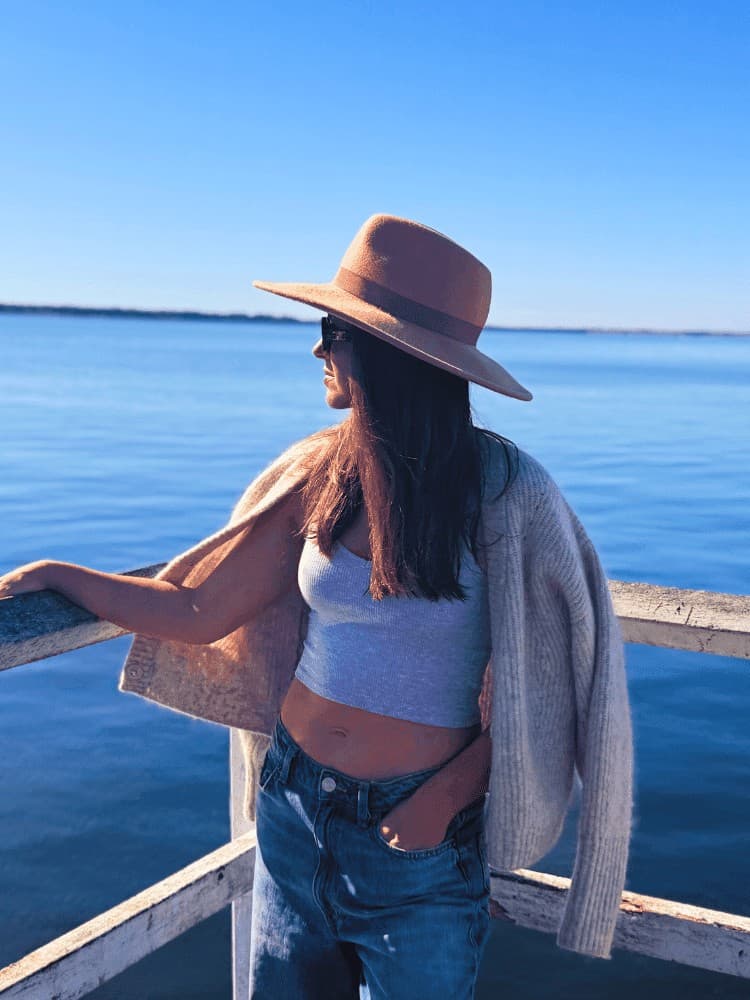 Woman in a wide-brimmed hat and cardigan looking out over the water at Bannisters Port Stephens