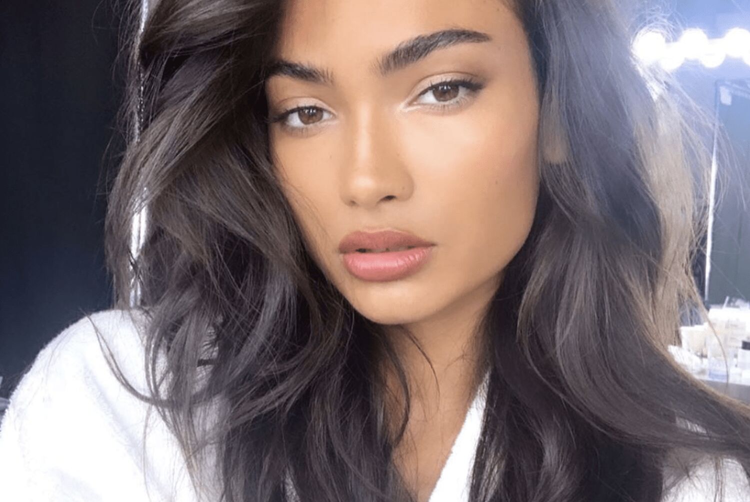 Woman with voluminous, glossy blowdried hair using a round brush and professional hairdryer