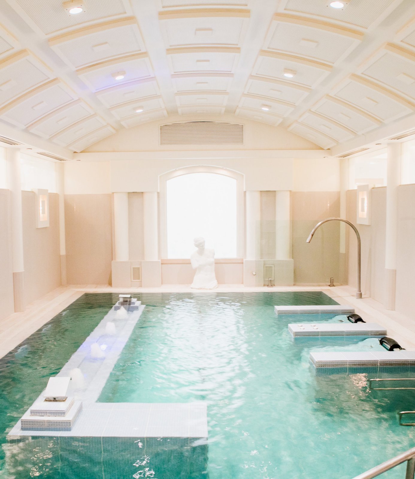 Roman-style hydrotherapy pool with massage jets and a classical statue beneath a vaulted ceiling at Noosa Springs Spa