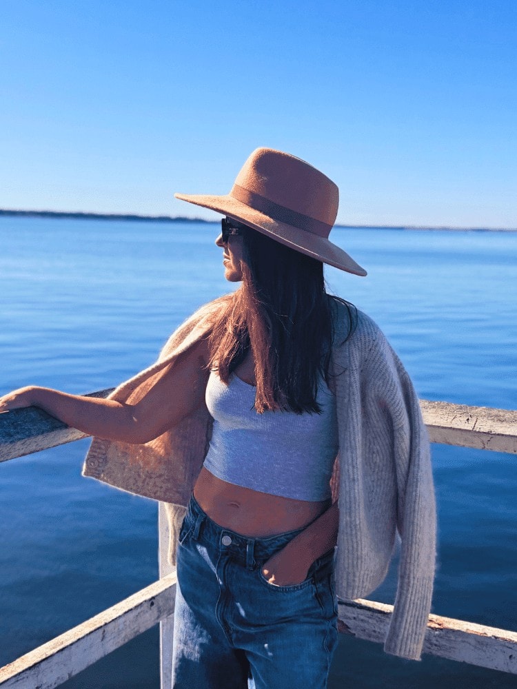 Woman in a wide-brimmed hat and cardigan looking out over the water at Bannisters Port Stephens