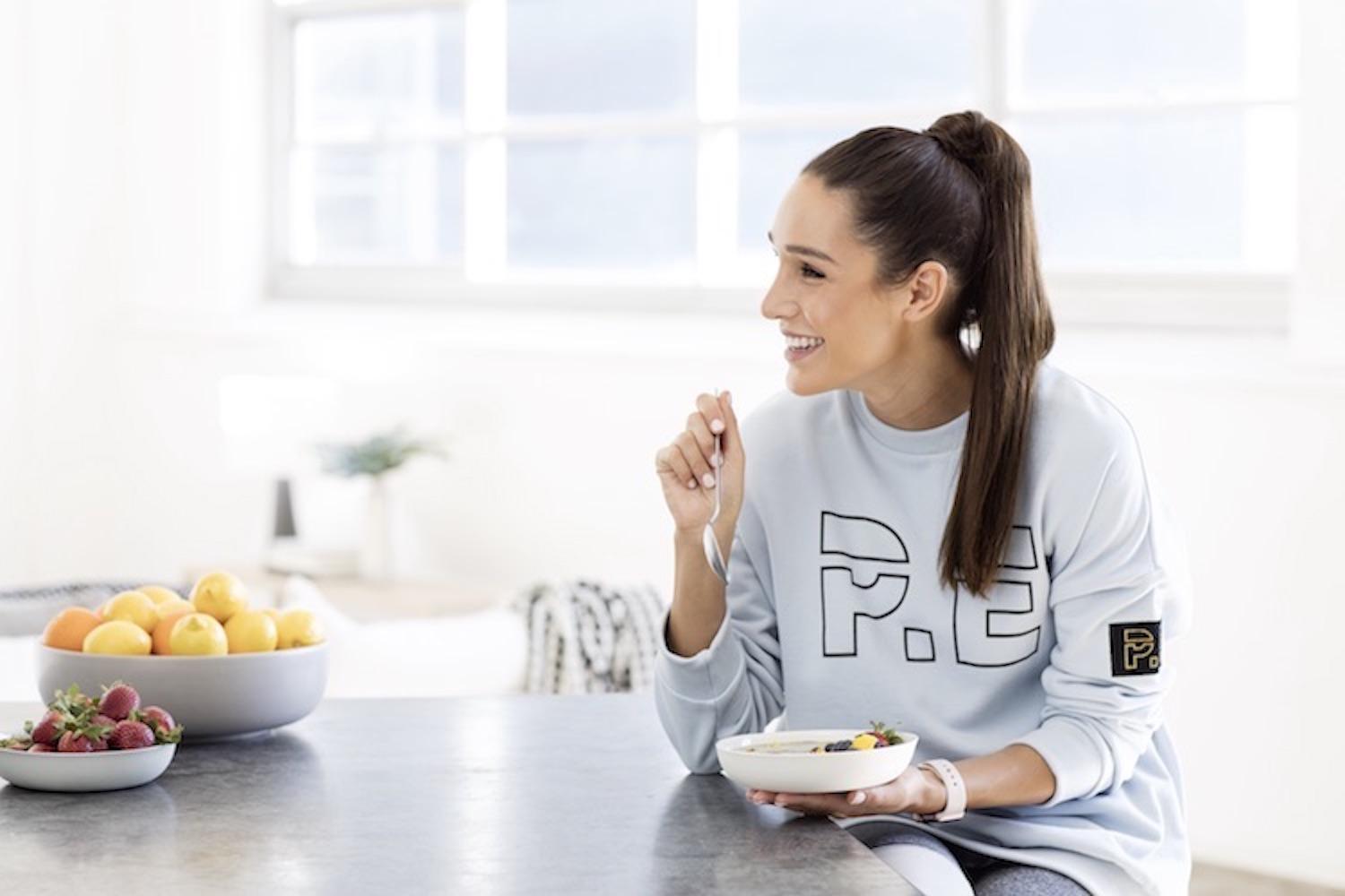 Kayla Itsines in athletic wear, minimal makeup, natural skincare glow