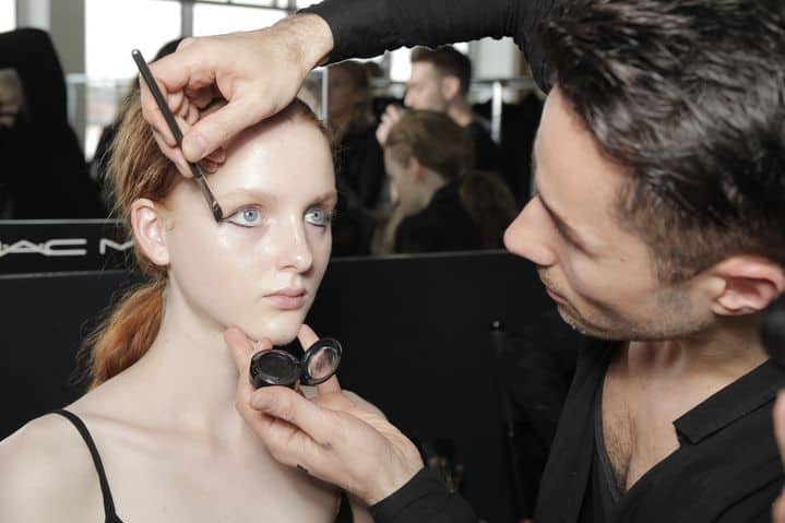 Professional makeup artist applying cosmetics backstage at fashion week runway show