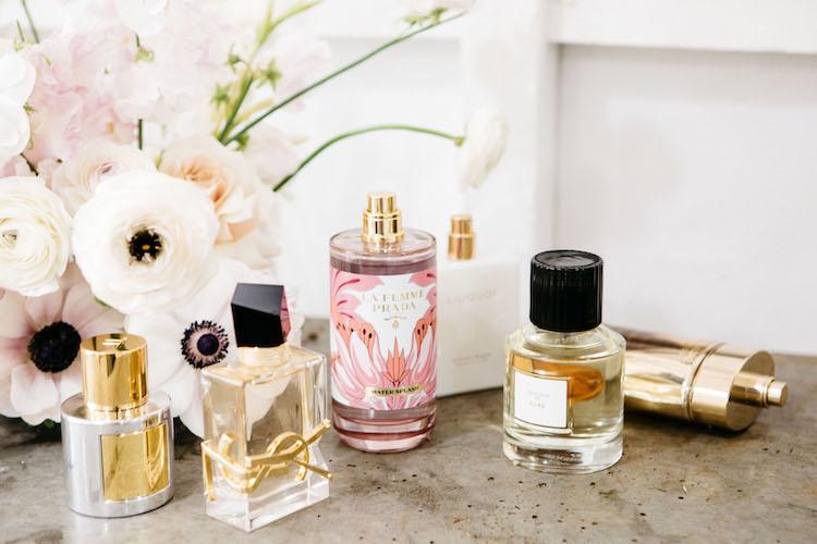 Luxury spring perfume bottles arranged with fresh flowers and green foliage