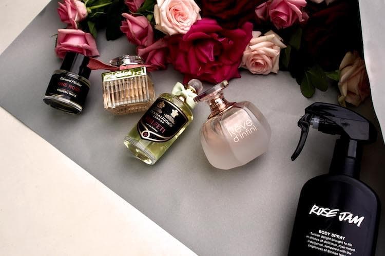 Luxury rose perfume bottles arranged with fresh rose petals and blooms
