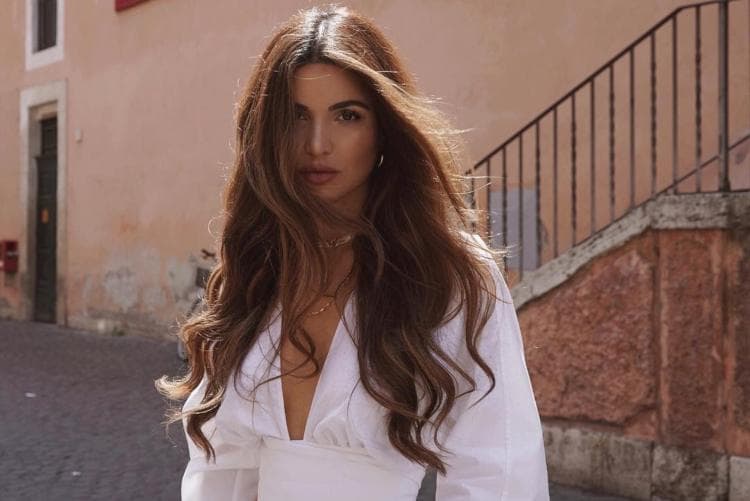 Woman with long, voluminous hair extensions styled in loose waves, showcasing length and shine