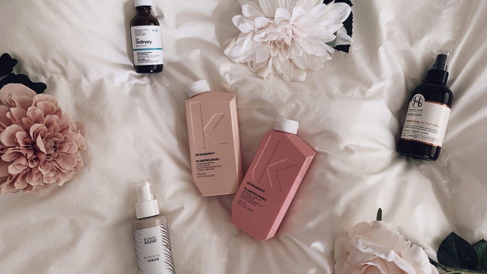 Selection of premium hair care products including shampoo, serum and oil treatments arranged on a neutral surface