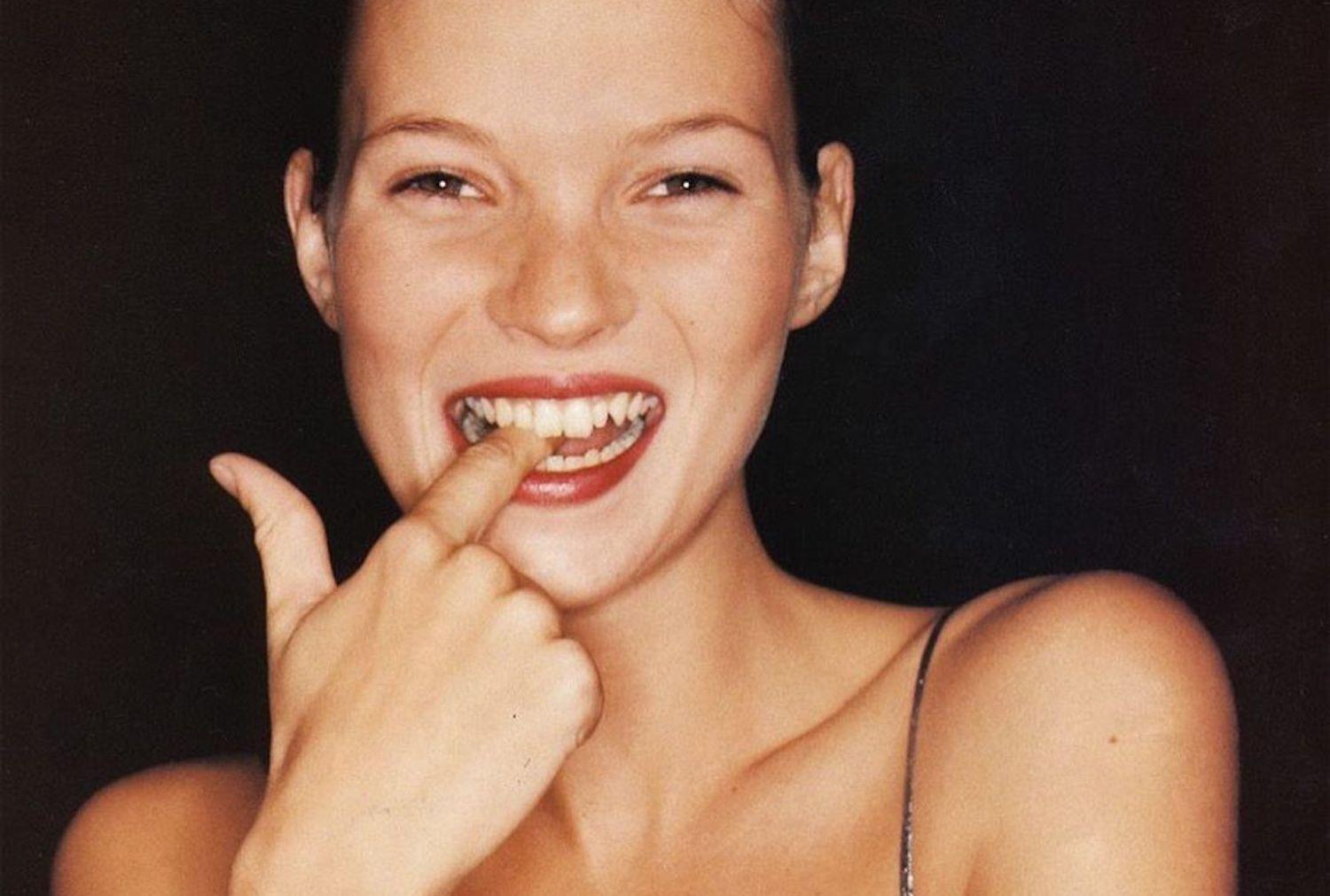 Woman applying minimal makeup at home, holding a small pot of foundation with natural lighting