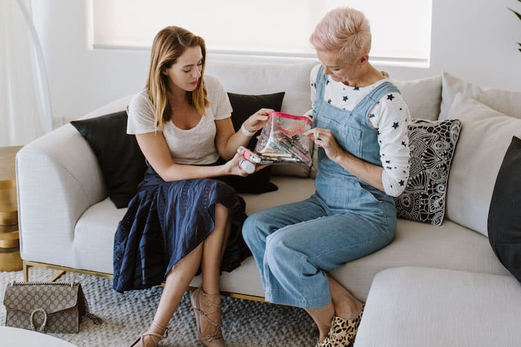 Jessica Rowe holding her cat-themed beauty bag and showing her favourite makeup products