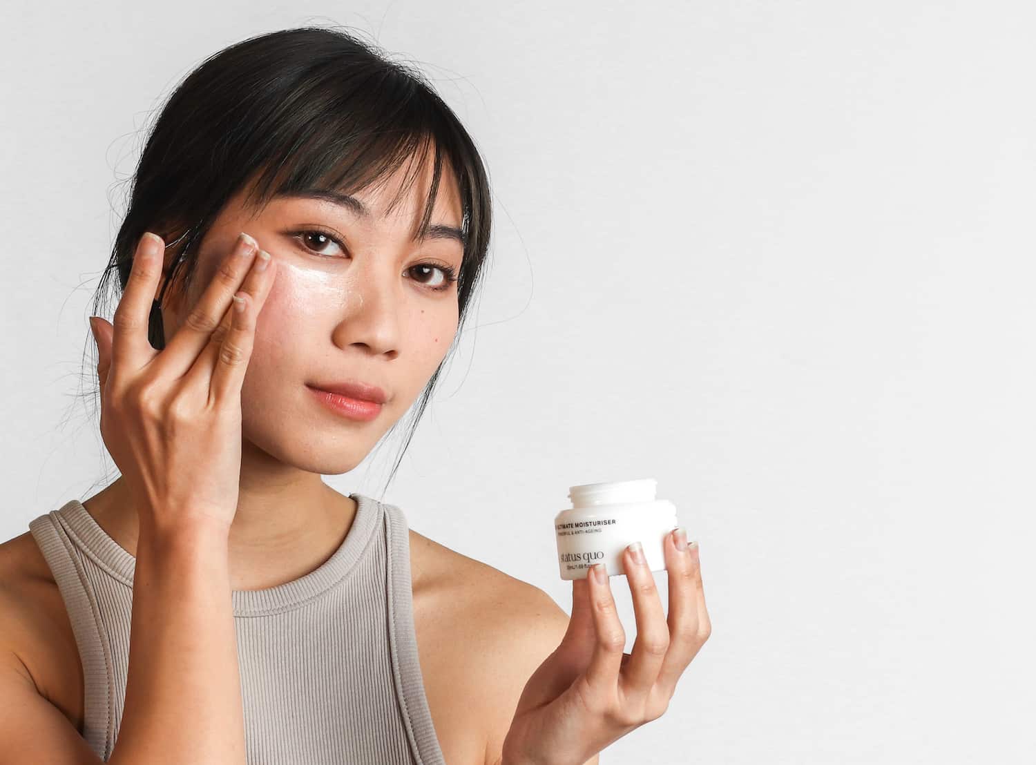 Woman with glowing, healthy complexion applying lightweight serum to cheek