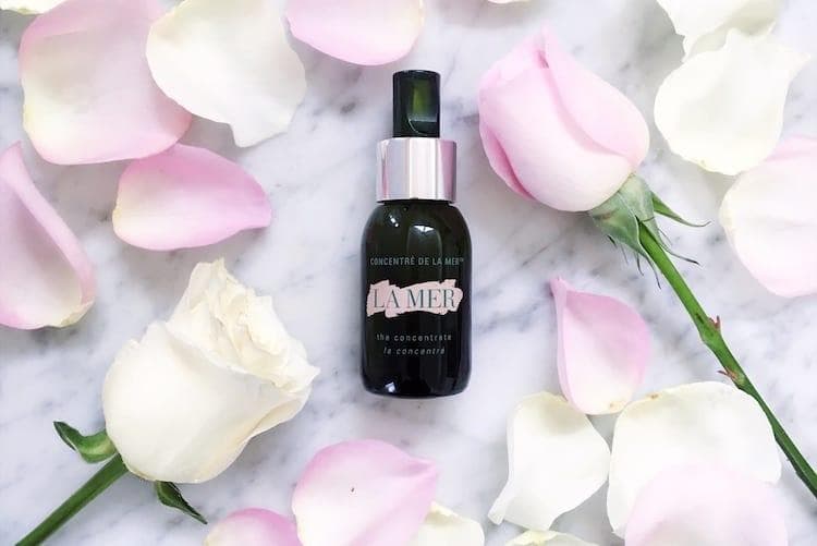 La Mer The Concentrate in deep green glass bottle displayed with skincare products on marble surface