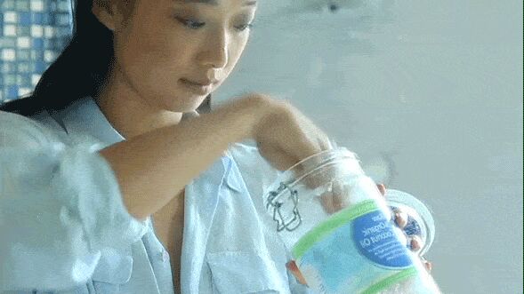 Woman applying melted coconut oil to face as makeup remover during skincare routine