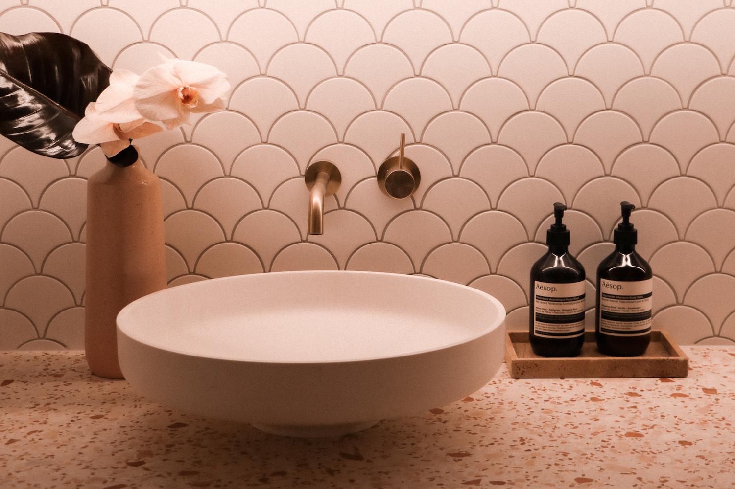 Elegant cosmetic clinic interior with pale grey and pink furnishings, ethereal artwork and blush-toned treatment sink