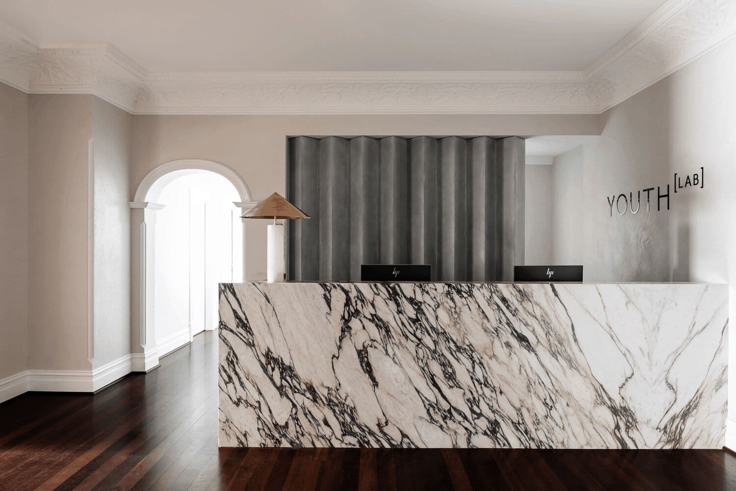 Modern luxury skincare clinic interior with marble fixtures, brass fittings, and contemporary art installation