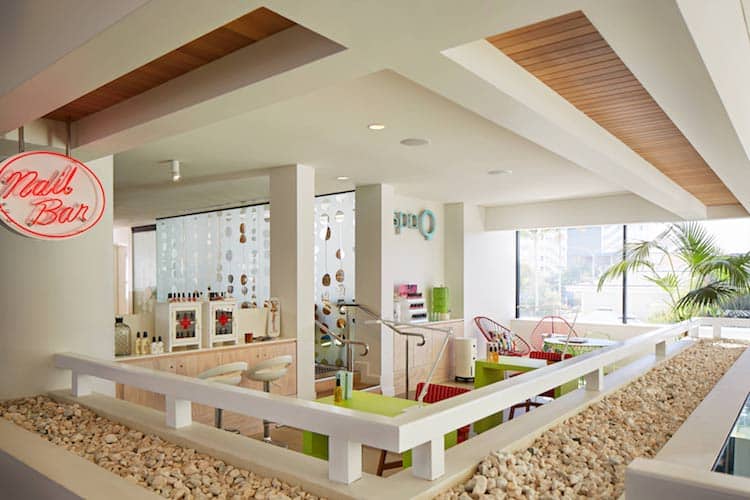 Bright spa reception area with neon Spa Q signage, colourful décor and beachy cane furnishings at QT Hotel Gold Coast