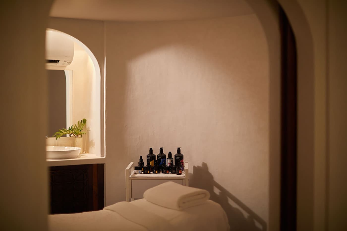 Luxurious spa treatment room with champagne mother-of-pearl tiled walls, arched Moroccan doorways, and soft golden lighting at Rae's Spa