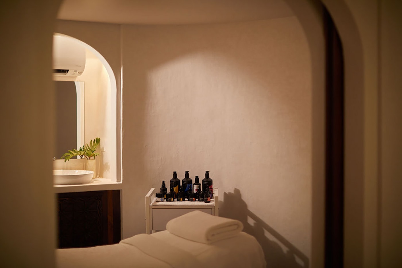 Luxurious spa treatment room with champagne mother-of-pearl tiled walls, arched Moroccan doorways, and soft golden lighting at Rae's Spa