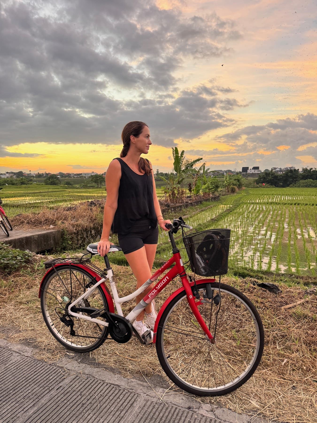 Sigourney wheeling her bike along the track between the Canggu rice paddies as the sun comes up on the Escape Haven morning ride