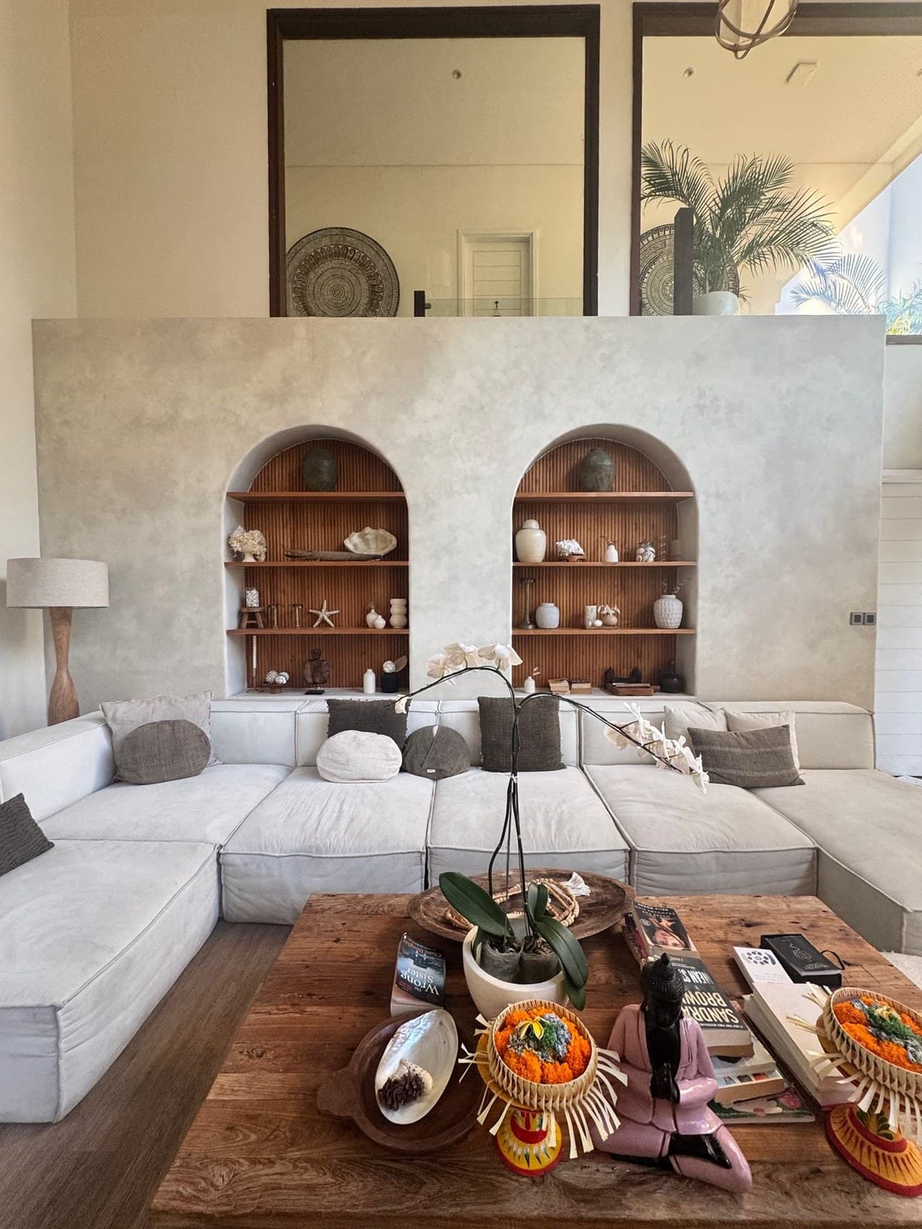 The communal lounge at Escape Haven Bali, low linen sofas and arched niches holding shells and ceramics