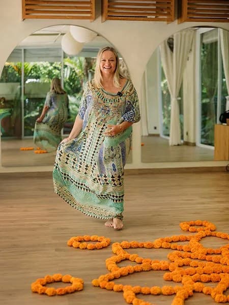 Janine Hall, founder of Escape Haven, walking through the retreat in a kaftan past marigold petals laid out across the floor