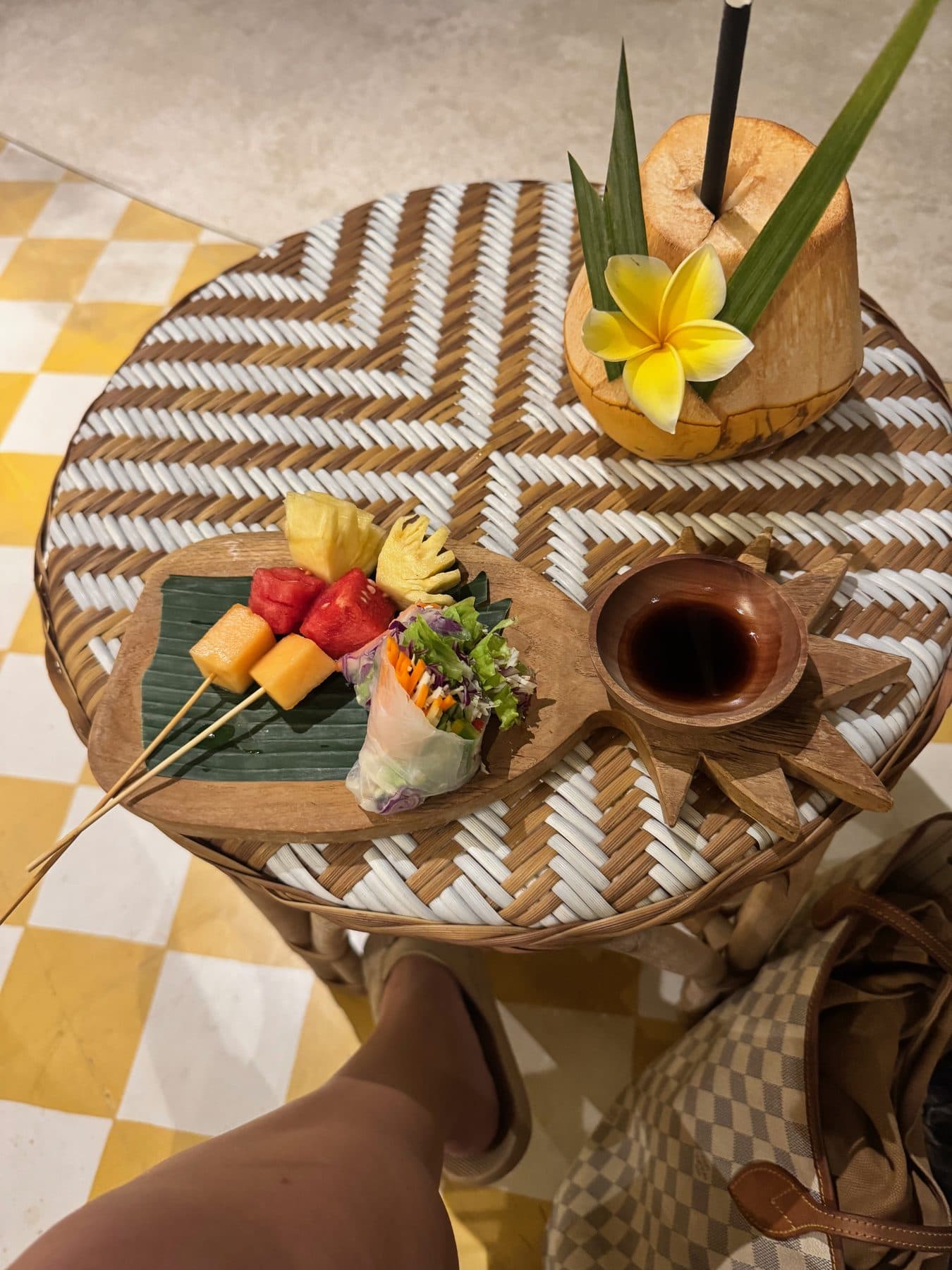 The welcome coconut, Vietnamese spring roll and fruit skewer set out on a rattan table on arrival at Escape Haven, Canggu