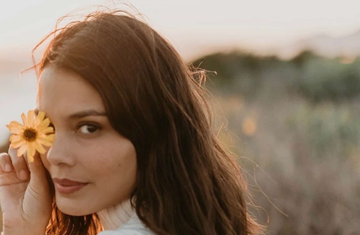 Nathalie Kelley in her garden surrounded by herbs and plants, wearing casual sustainable clothing