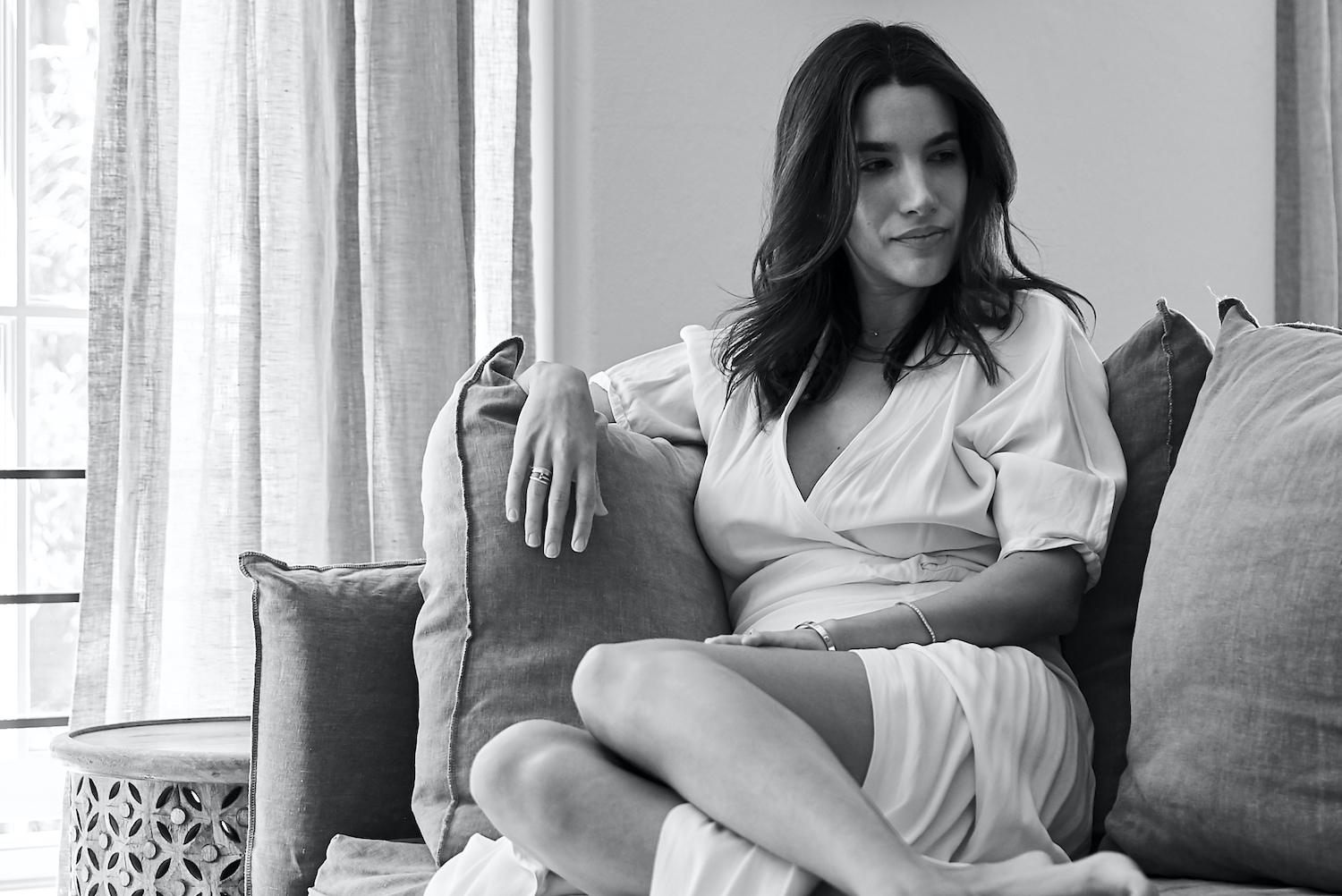 Natalia Kindler with natural curled hair, minimal makeup, wearing neutral tones in a wellness-focused lifestyle setting