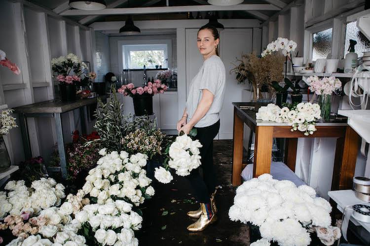 Woman with glowing skin holding fresh flowers, minimal makeup aesthetic