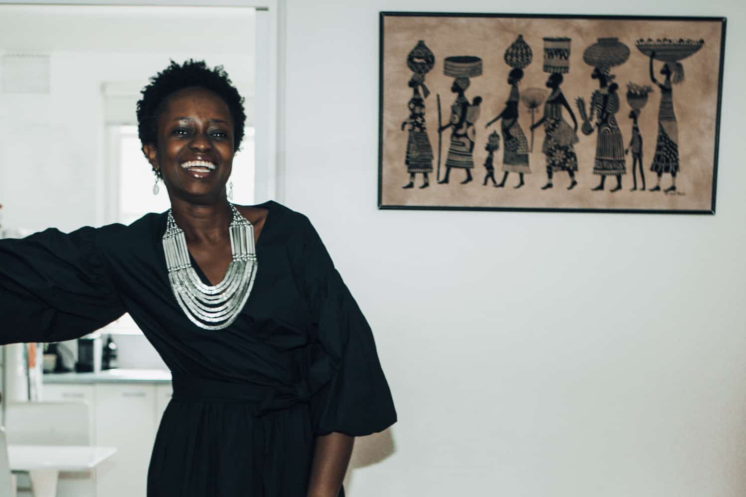 Portrait of Aminata Conteh-Biger wearing a cream Oroton placket detail dress against a neutral background