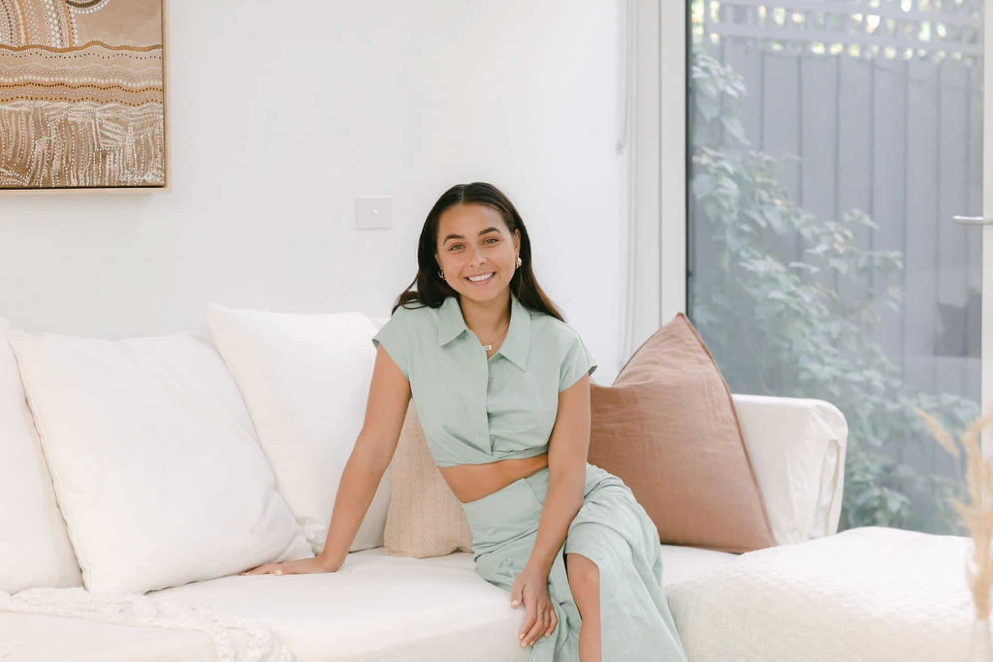 Brooke Blurton at home in Melbourne, seated on her neutral-toned couch