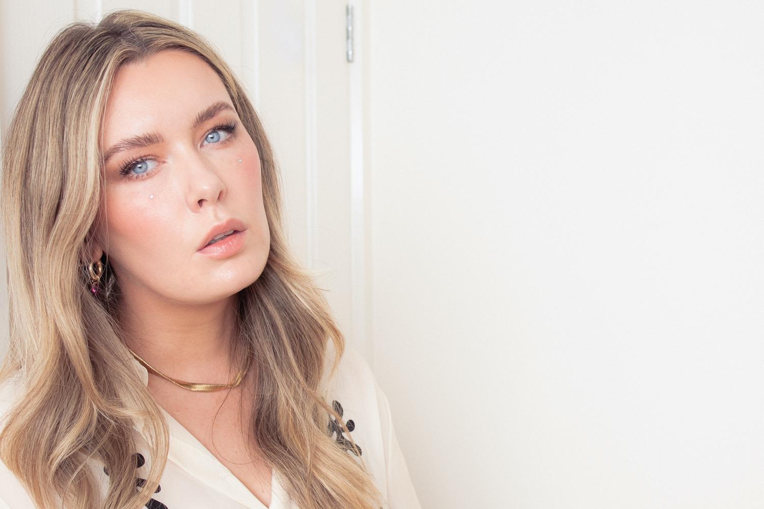 Portrait of Hannah English, a female scientist and beauty influencer, in a professional setting with skincare products visible