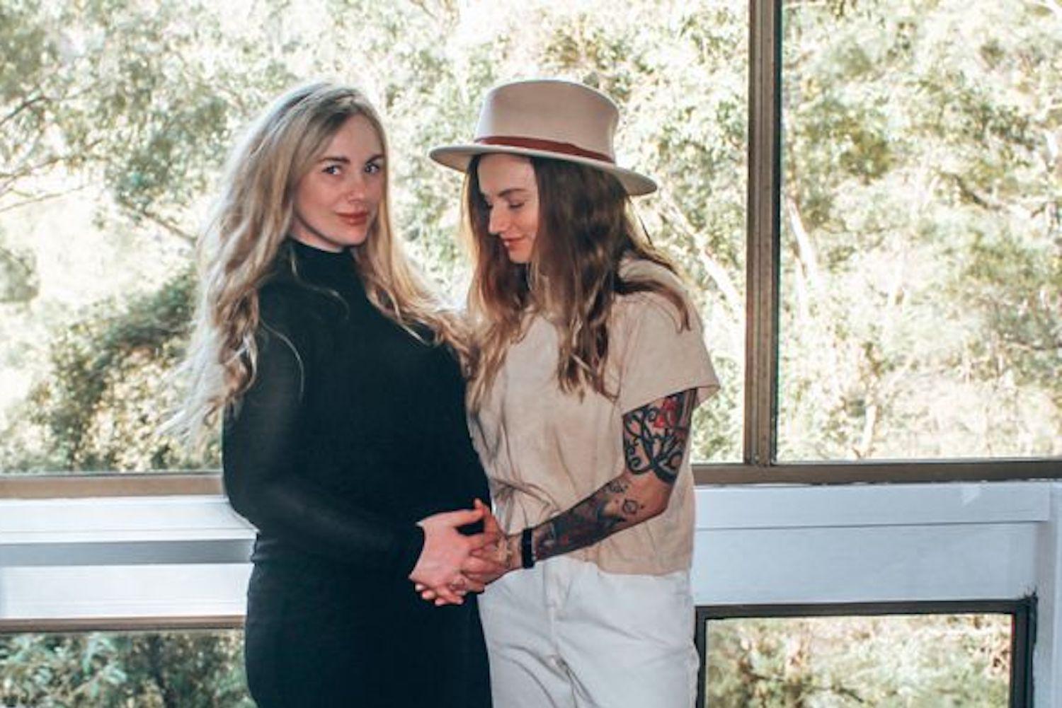 Jessi and Millie Poutama in wedding attire on their wedding day, standing together outdoors