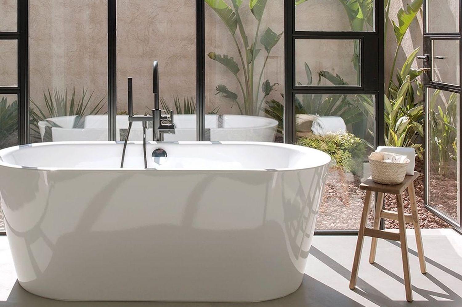 Luxurious modern bathroom with marble vanity, statement mirror, gold accessories and potted plants