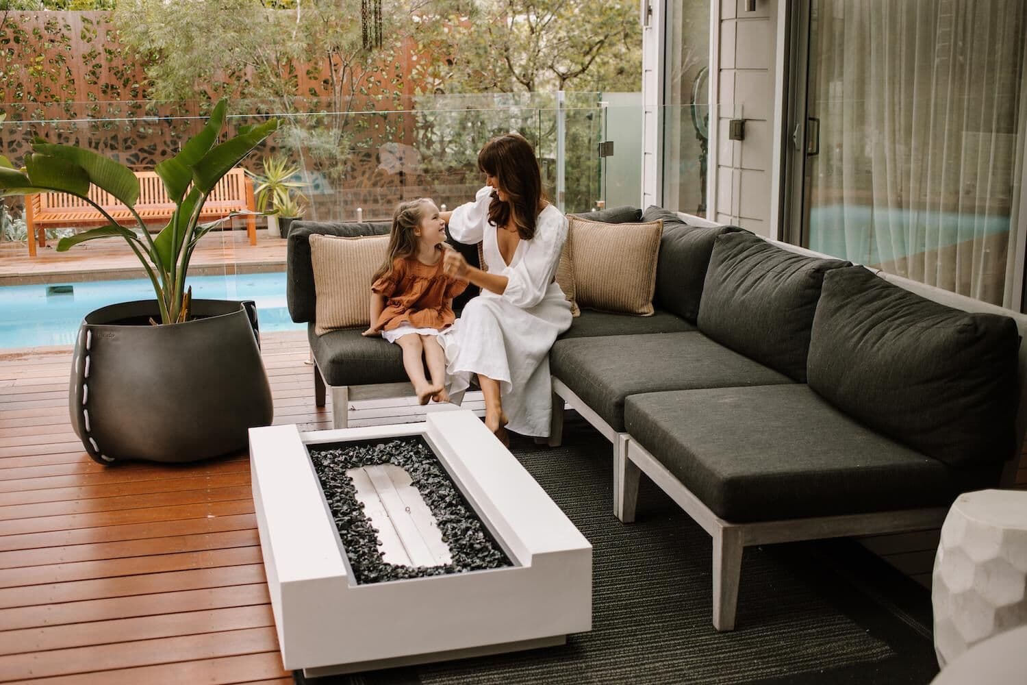 Round bone-coloured EcoSmart Fire Table with lit flames on a modern outdoor patio