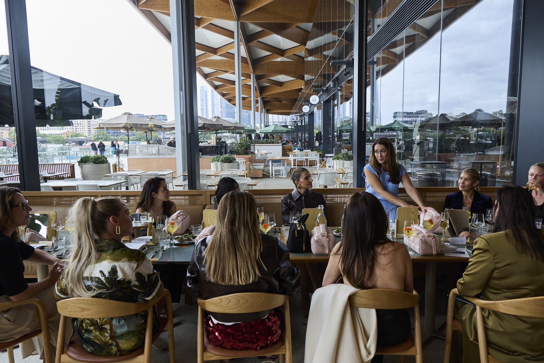 The dining room at Lua, with guests seated along the long table beside floor-to-ceiling windows over the harbour