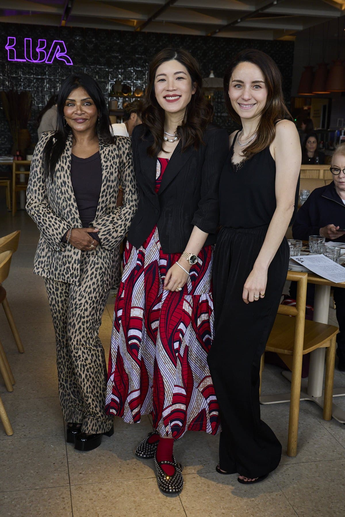Three guests standing together in front of the neon Lua sign