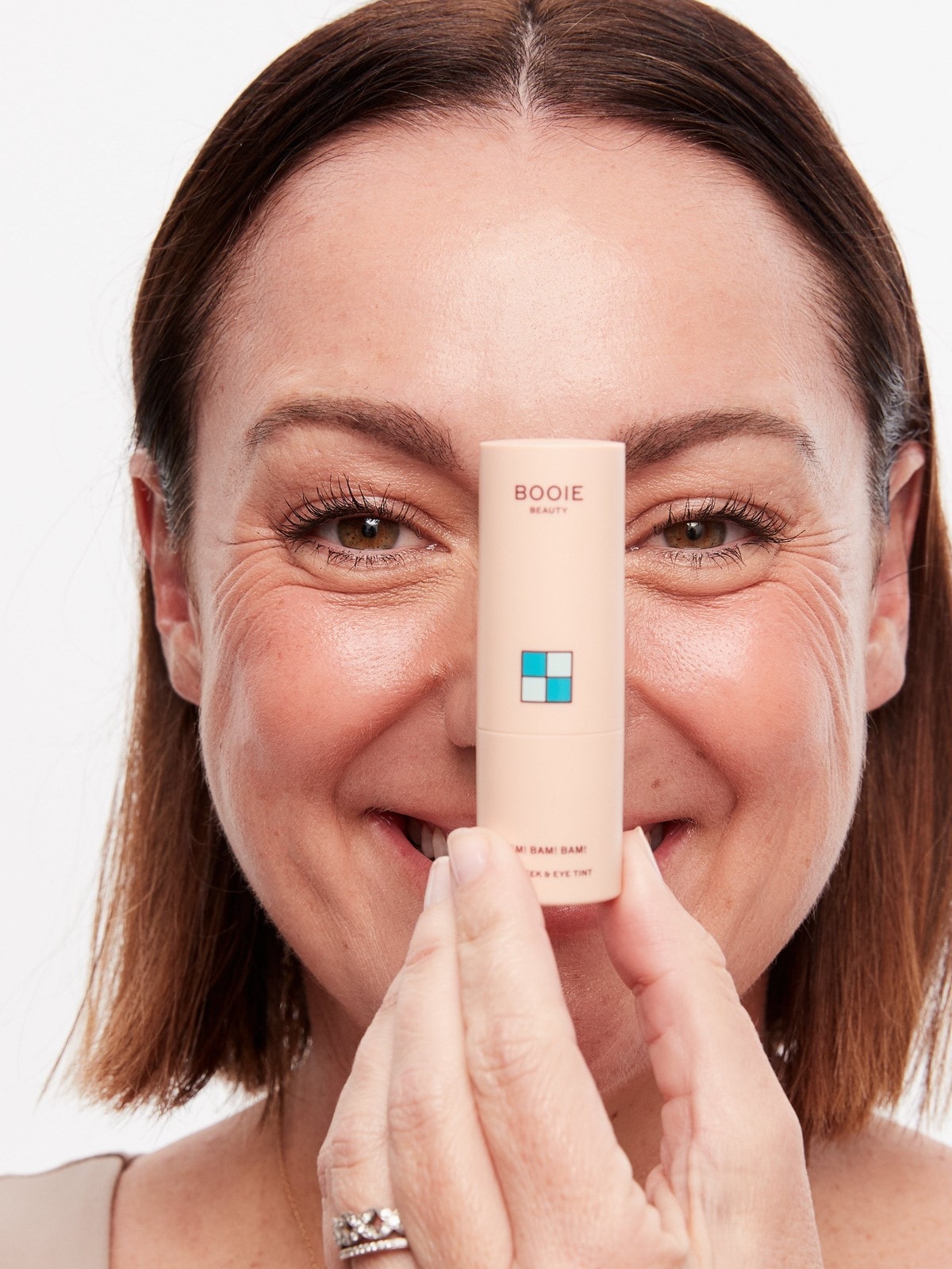 Celeste Barber holding a BOOIE Beauty Bam! Bam! Bam! tint up to her eye