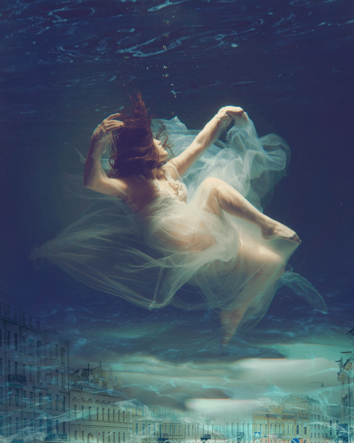 An ethereal underwater portrait of a woman floating in flowing fabric
