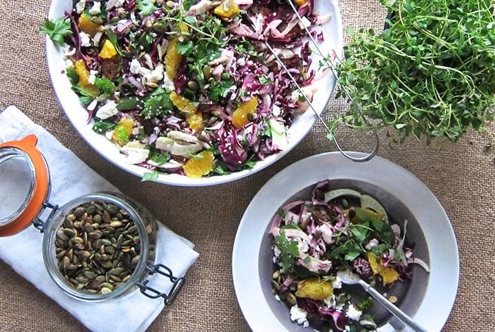 Colourful rainbow salad with red cabbage, orange slices, dates, crumbled feta and sesame seeds