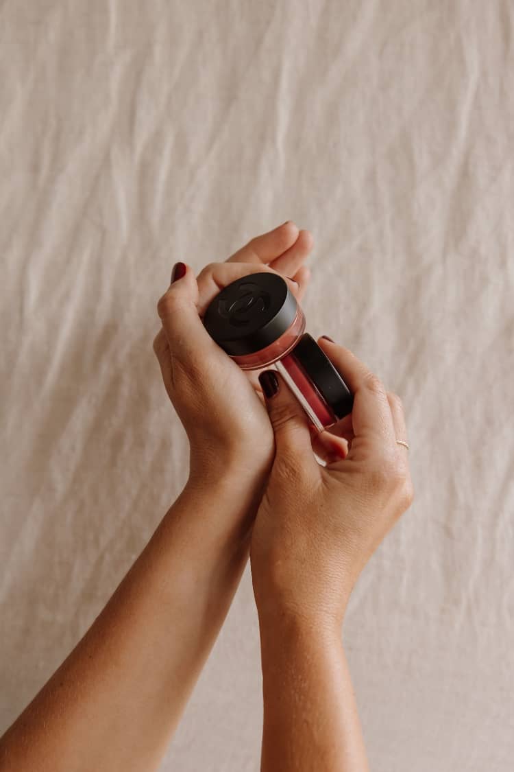 Hands opening the No 1 de Chanel Lip and Cheek Balm showing the bio-material camellia lid