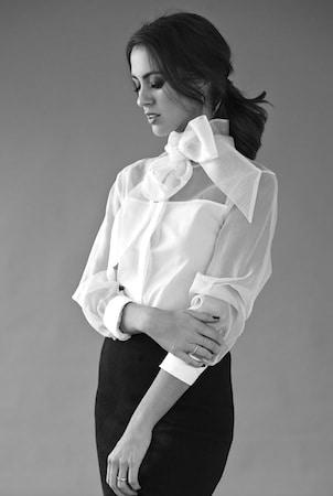 Sigourney Cantelo in a classic white button-down shirt with minimal makeup and scraped-back hair
