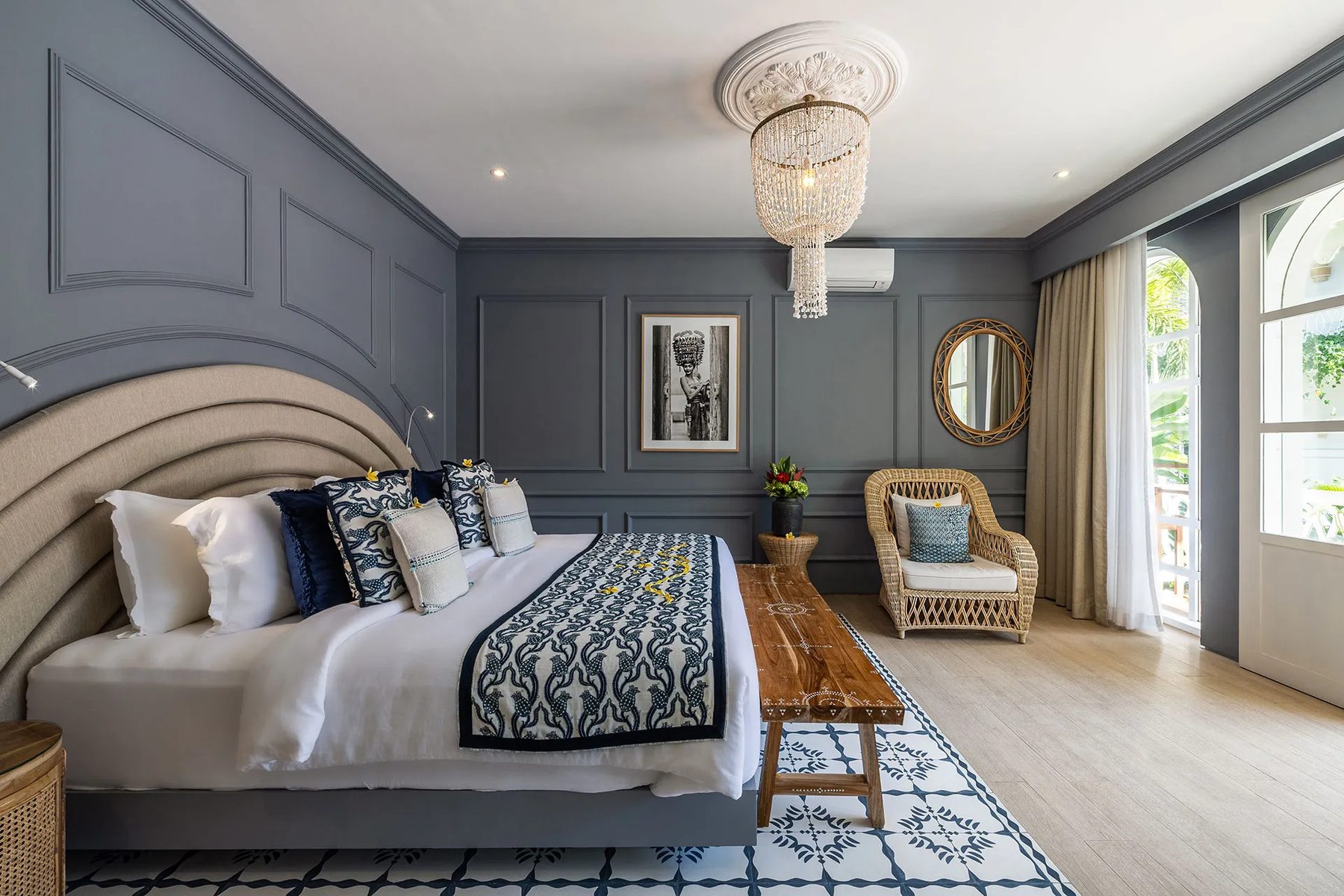 A goddess room at Escape Haven Bali, panelled in deep grey with a beaded chandelier, arched bedhead and doors open to the garden