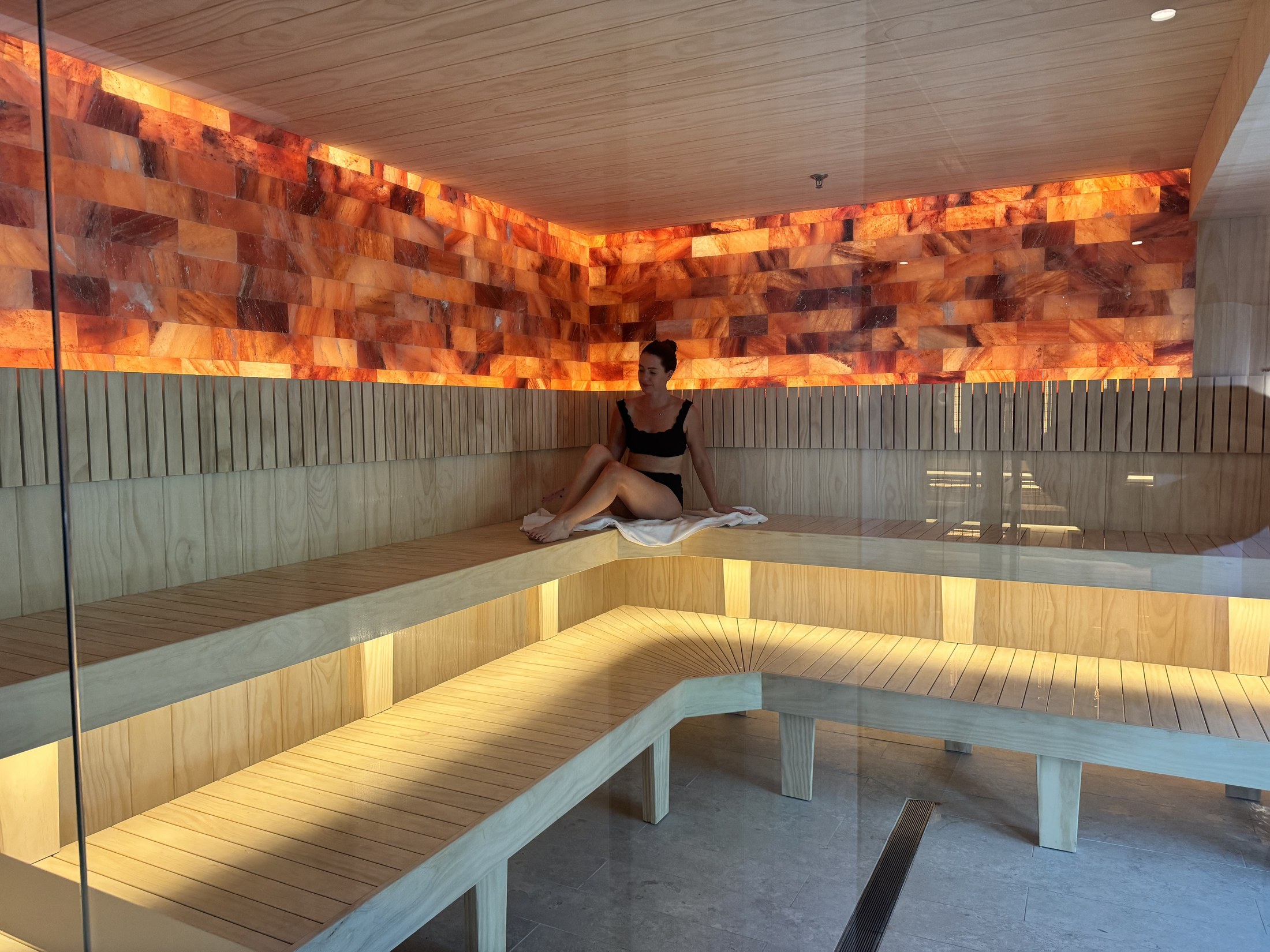 Inside the salt brick sauna at Eliva Spa, backlit Himalayan salt walls and tiered timber benches