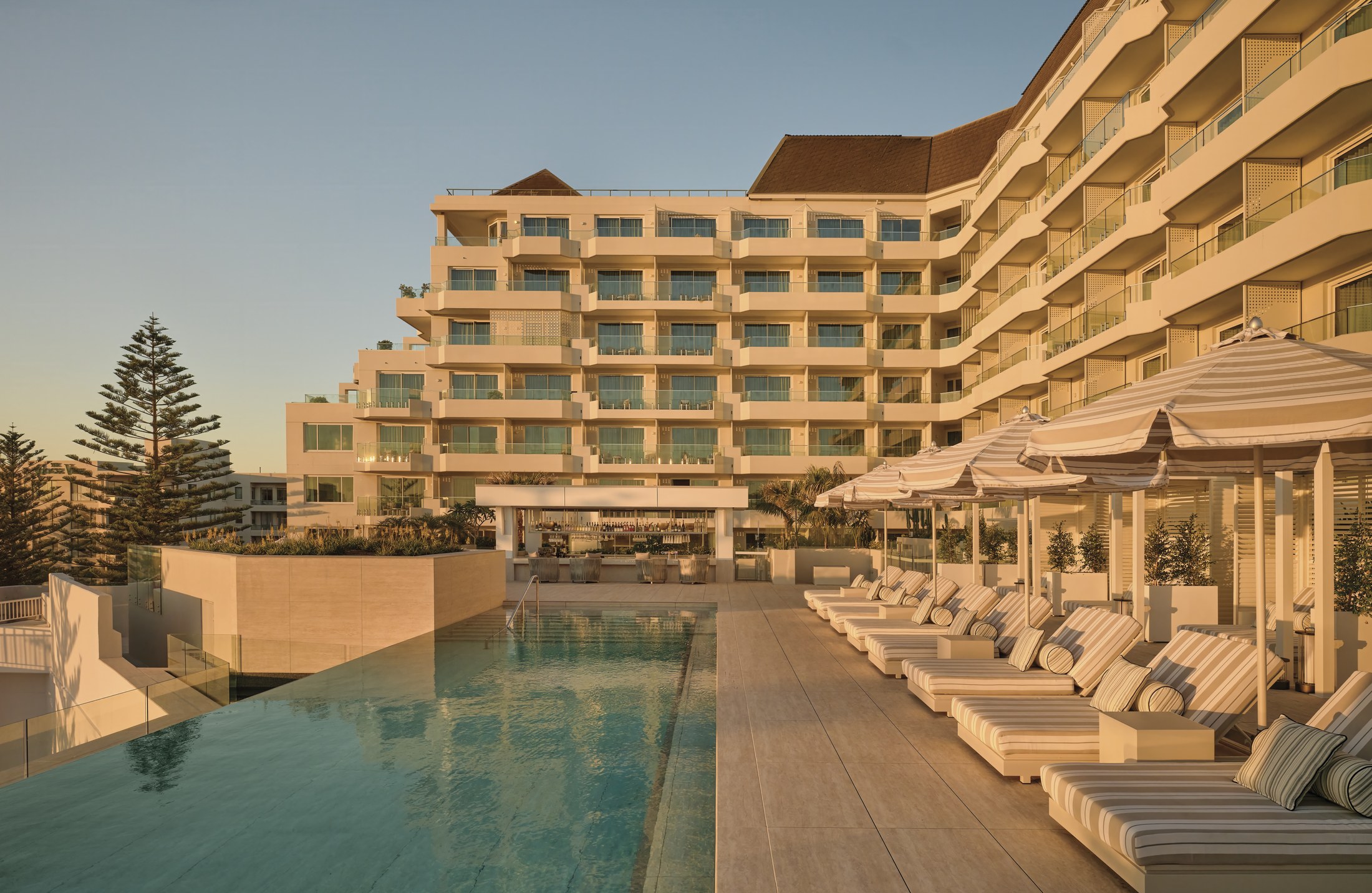The InterContinental Sydney Coogee Beach seen from the oceanfront pool deck, with striped daybeds along the water's edge