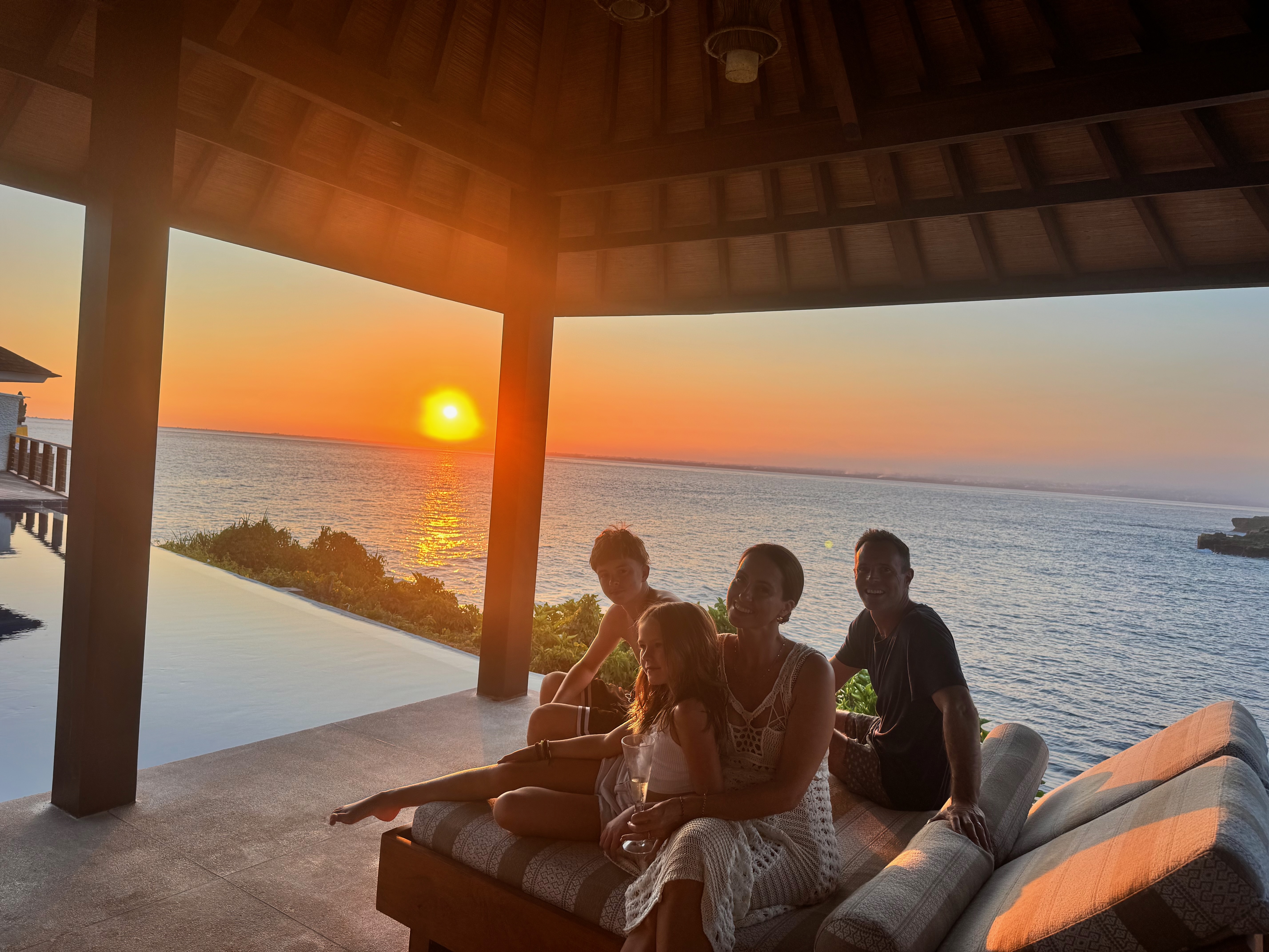 The four of us under the thatched pavilion at Villa Tranquilla, watching the sun go down