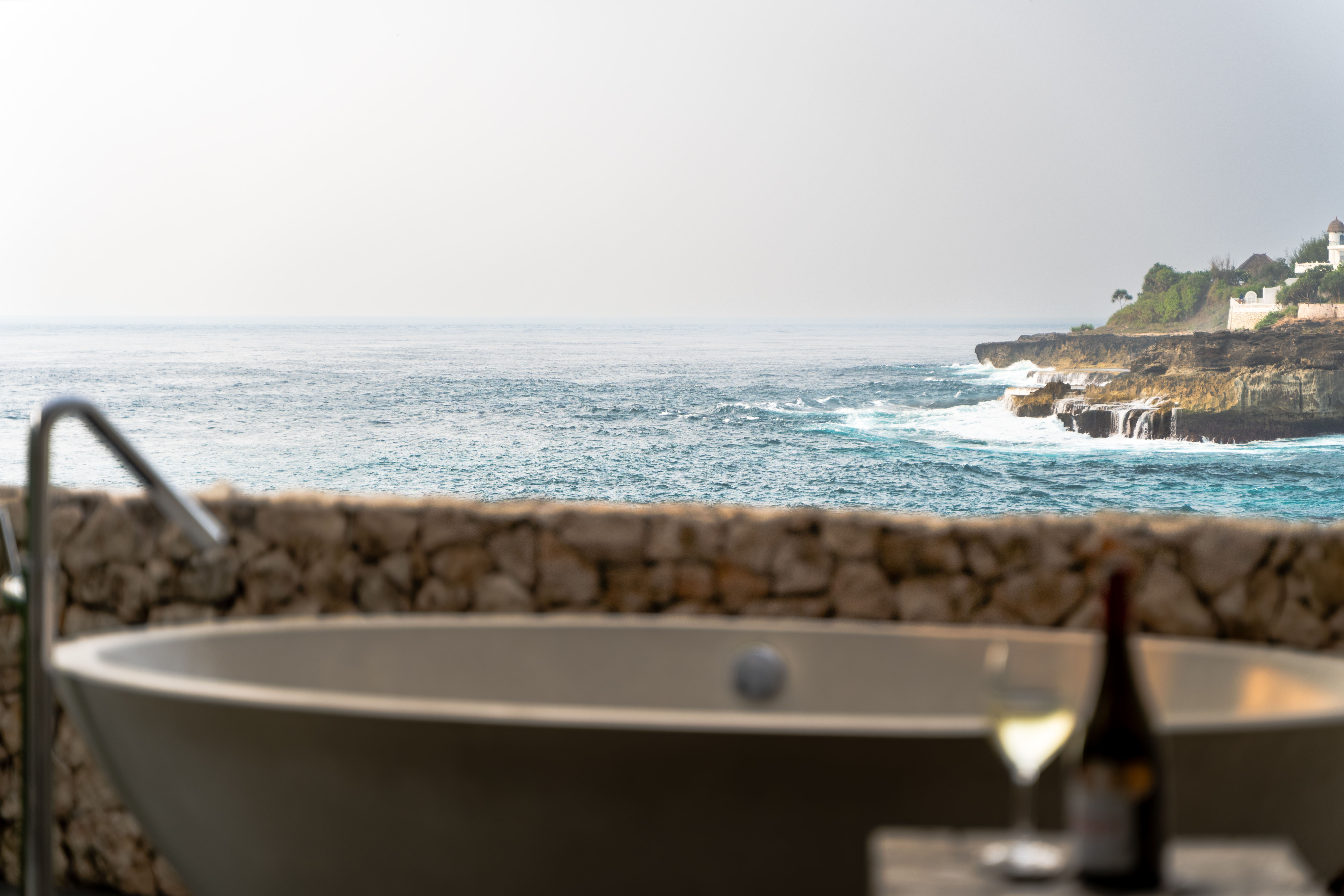 The outdoor bathtub at Villa Tranquilla — ocean views, stone terrace, and a very good bottle of wine