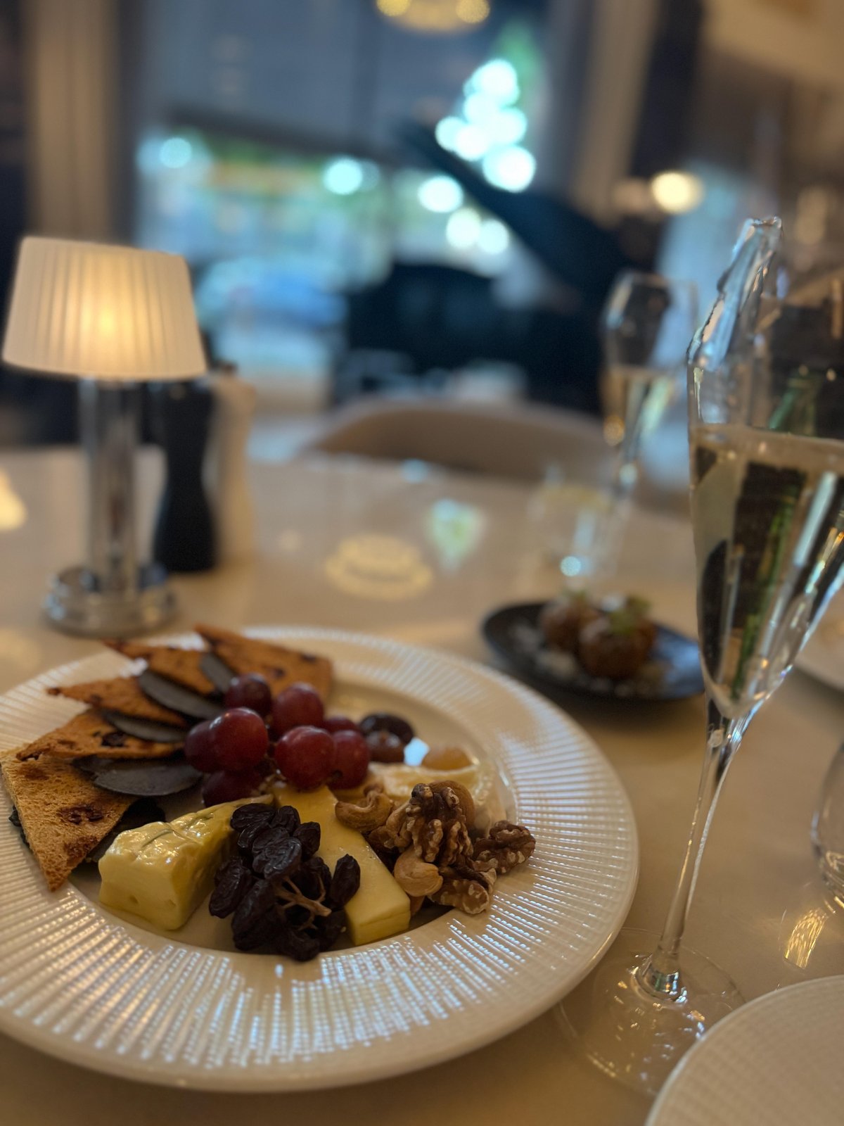 A share plate of cheeses, grapes and walnuts beside a glass of champagne at The Royce Hotel Melbourne