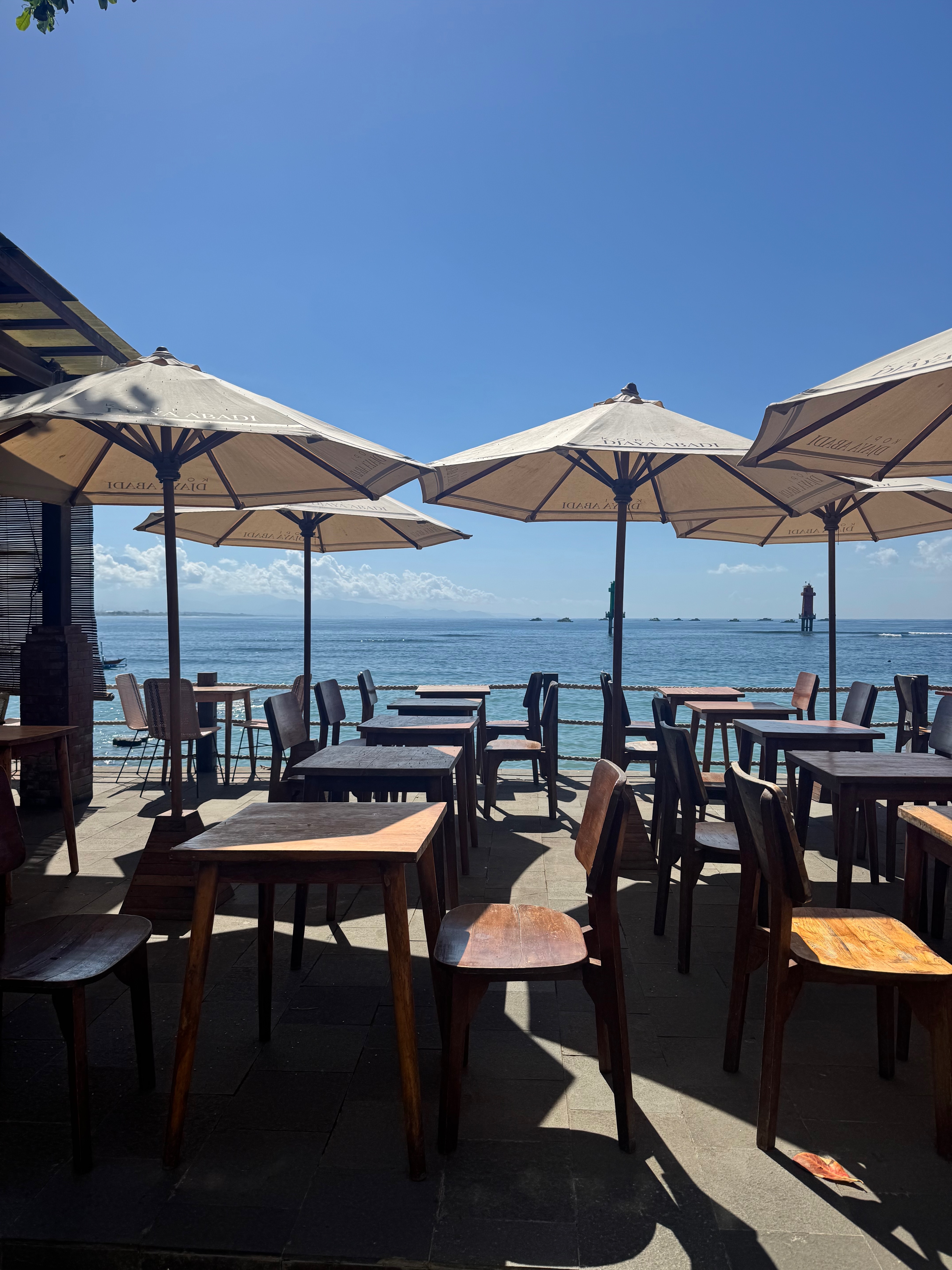 A row of colourful cafes and warungs along the Sanur beachfront strip, buzzing with local life