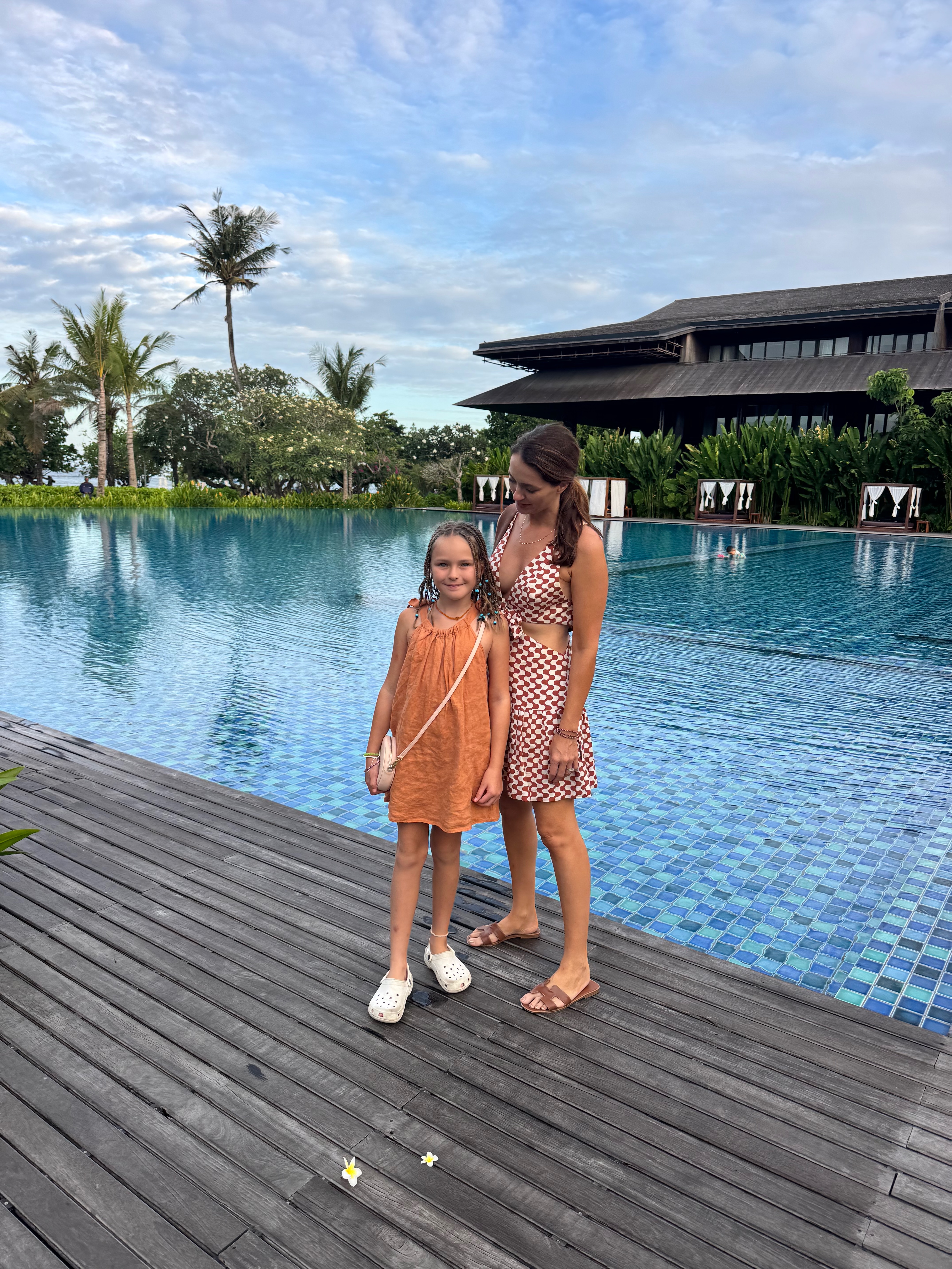 The infinity pool at The Meru Sanur surrounded by tropical gardens, sun loungers and dramatic resort architecture
