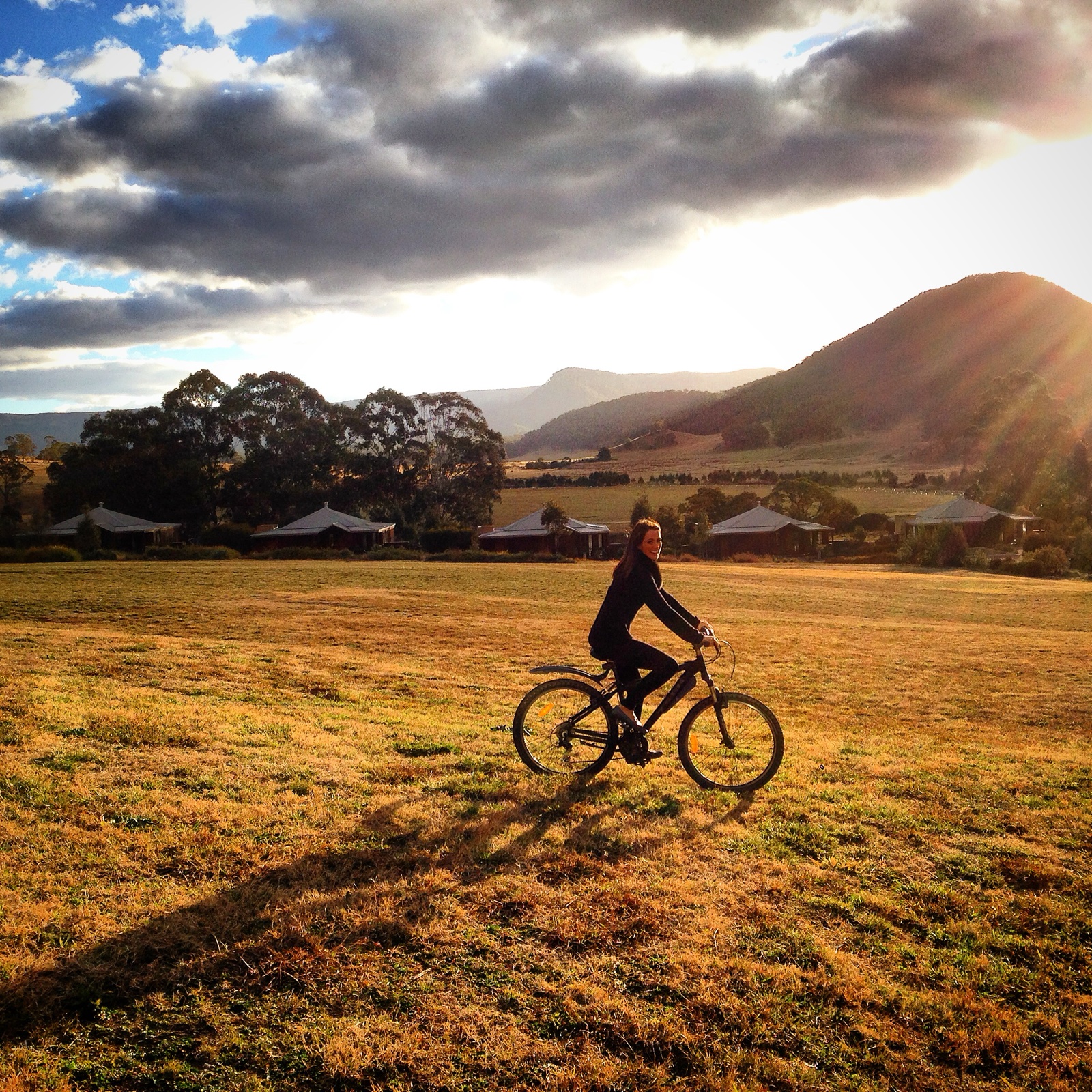 Cycling through Wolgan Valley at golden hour with mountains and villas behind