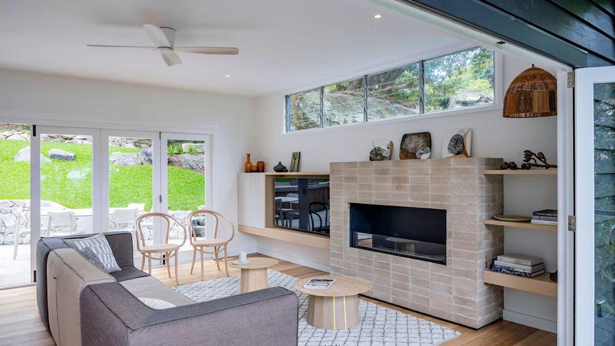 Open-plan living area at Crane Lodge with blonde timber and large sliding windows open to the forest